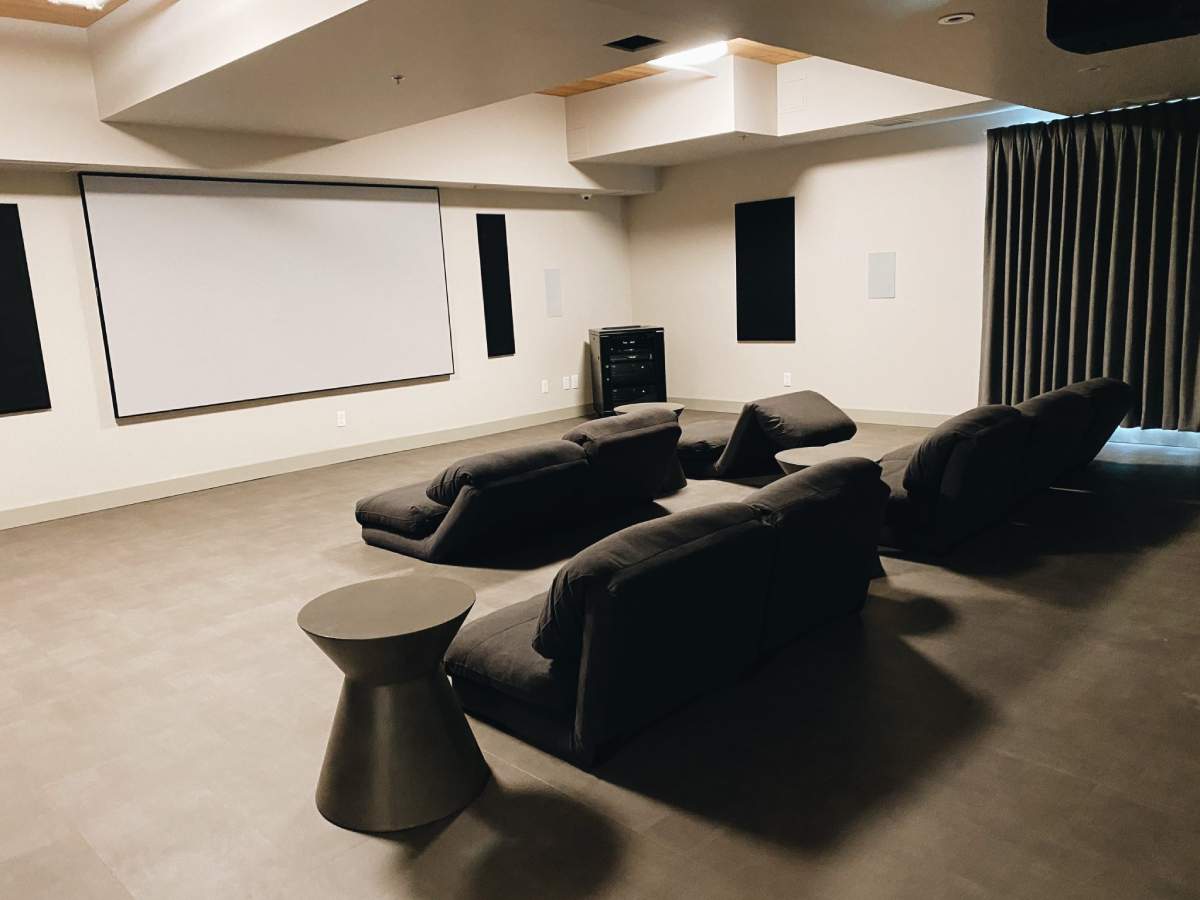 A private movie theatre room with a large projection screen and several plush recliners.